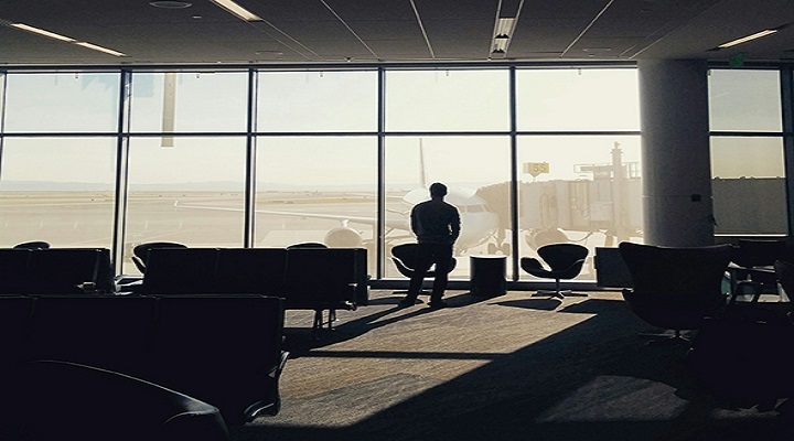 Rear View Of Man Standing In Waiting Area Of Airport