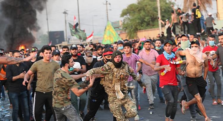 Anti-government protesters help a soldier from the Federal Police Rapid Response Forces to get out of the protest site area after other protesters beat him, in Baghdad, Iraq, Thursday, Oct. 3, 2019. Iraqi security forces fired live bullets into the air and used tear gas against a few hundred protesters in central Baghdad on Thursday, hours after a curfew was announced in the Iraqi capital on the heels of two days of deadly violence that gripped the country amid anti-government protests that killed over 19 people in two days. (AP Photo/Hadi Mizban)