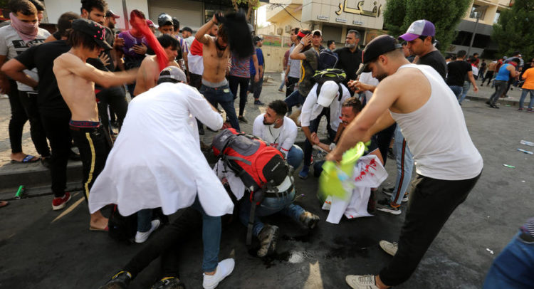 epa07886727 Iraqi protesters help a wounded protester who was wounded during clashes with Iraqi riot forces following a demonstration at al-Tahrir square, central Baghdad, Iraq, 01 October 2019. According to media reports, dozens of protesters were injured in the clashes that occurred as thousands of Iraqis were protesting over unemployment, the rising cost of living and lack of services in Baghdad. The Iraqi government had deployed a significant amount of military and police forces around the fortified green zone which is the headquarter of the Iraqi government in Baghdad.  EPA-EFE/AHMED JALIL