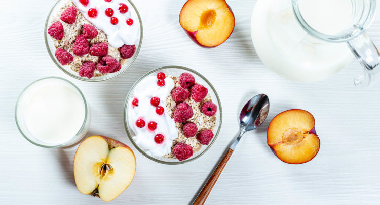 Bowl of healthy oatmeal with fresh berries and fruits with milk on white wooden background