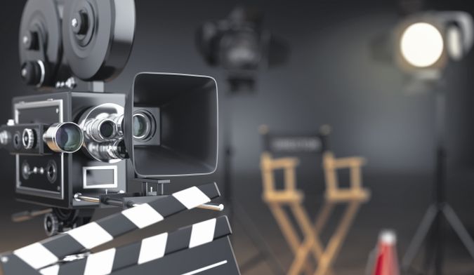 Video, movie, cinema concept. Retro camera, flash, clapperboard and director's chair in dark studio with dof effect. 3d