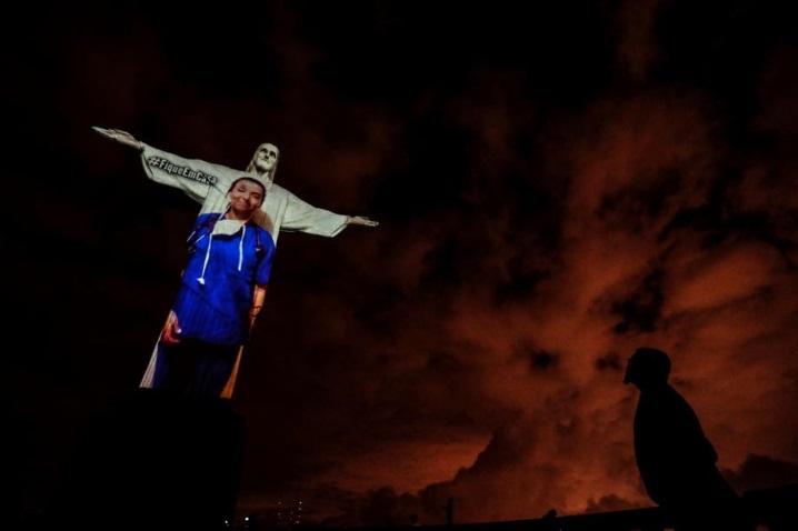 epa08359860 Christ the Redeemer statue is illuminated with the projection of a health worker image during a religious ceremony to celebrate Easter Sunday, on Mount Corcovado, Rio de Janeiro, Brazil, 12 April 2020. EPA-EFE/Antonio Lacerda