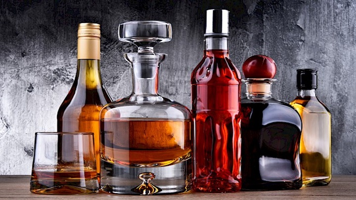 Composition with carafe and bottles of assorted alcoholic beverages.
